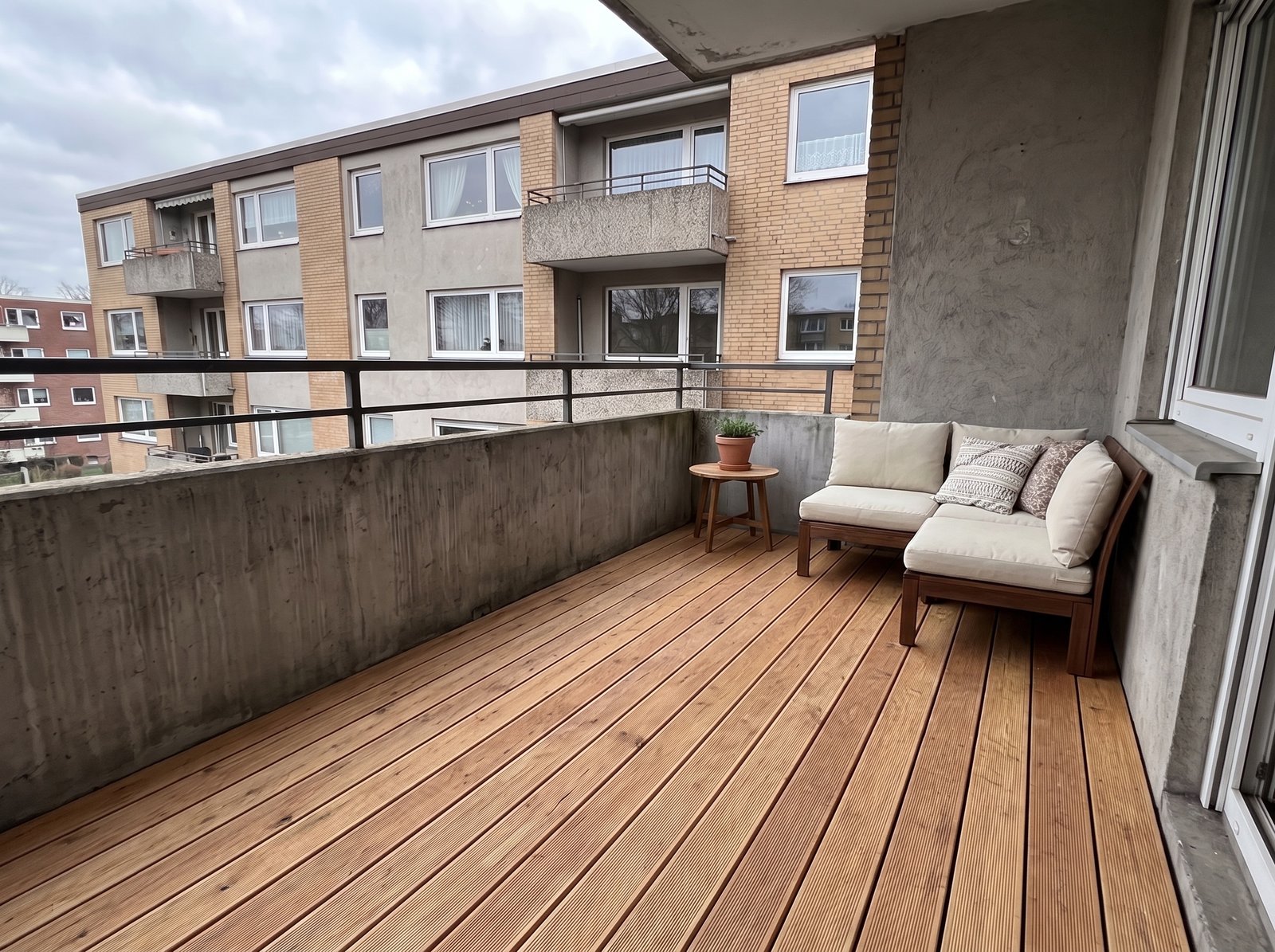 Balkon nach dem Makeover mit Holzterrasse und Sitzecke